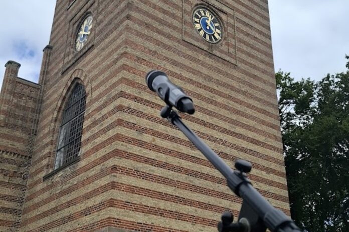 Lysprojektioner på Hobro Kirke under Vølvens Verden med kor og publikum på Kirketorvet.