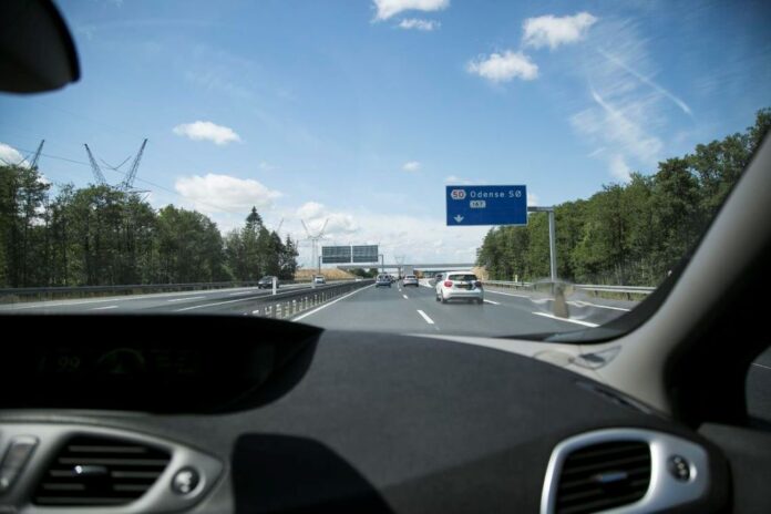 Bilist skifter vognbane på motorvej og bruger blinklys for at signalere manøvre.