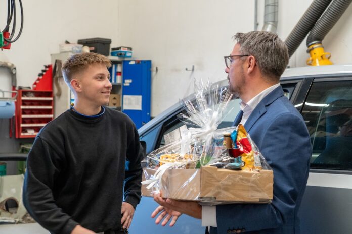 21-årige Marcus Bugge Raasdal Jensen fra Assens hædres af borgmester Jesper Skov Mikkelsen hos Therkildsen Biler i Hobro. Foto: Mariagerfjord Kommune.